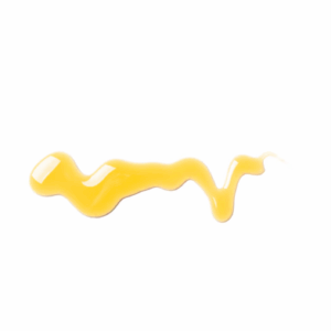 A thick, golden-yellow streak of castor oil is smeared across a white background.