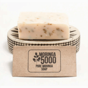 A bar of Moringa 5000 Pure Moringa Soap on a small soap dish.