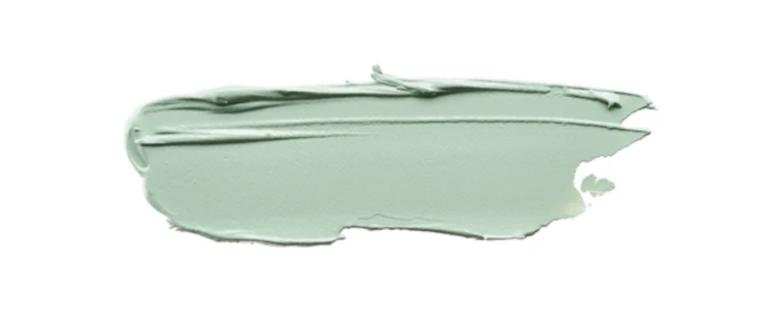 A thick smear of light green cream or clay on a white background.