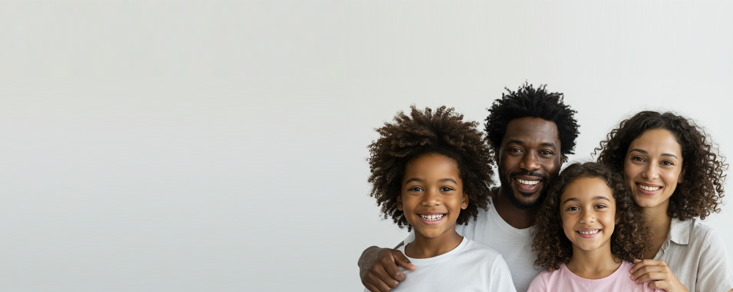 A smiling Black family, including a mother, father, and two children (a boy and a girl), standing together against a light background.